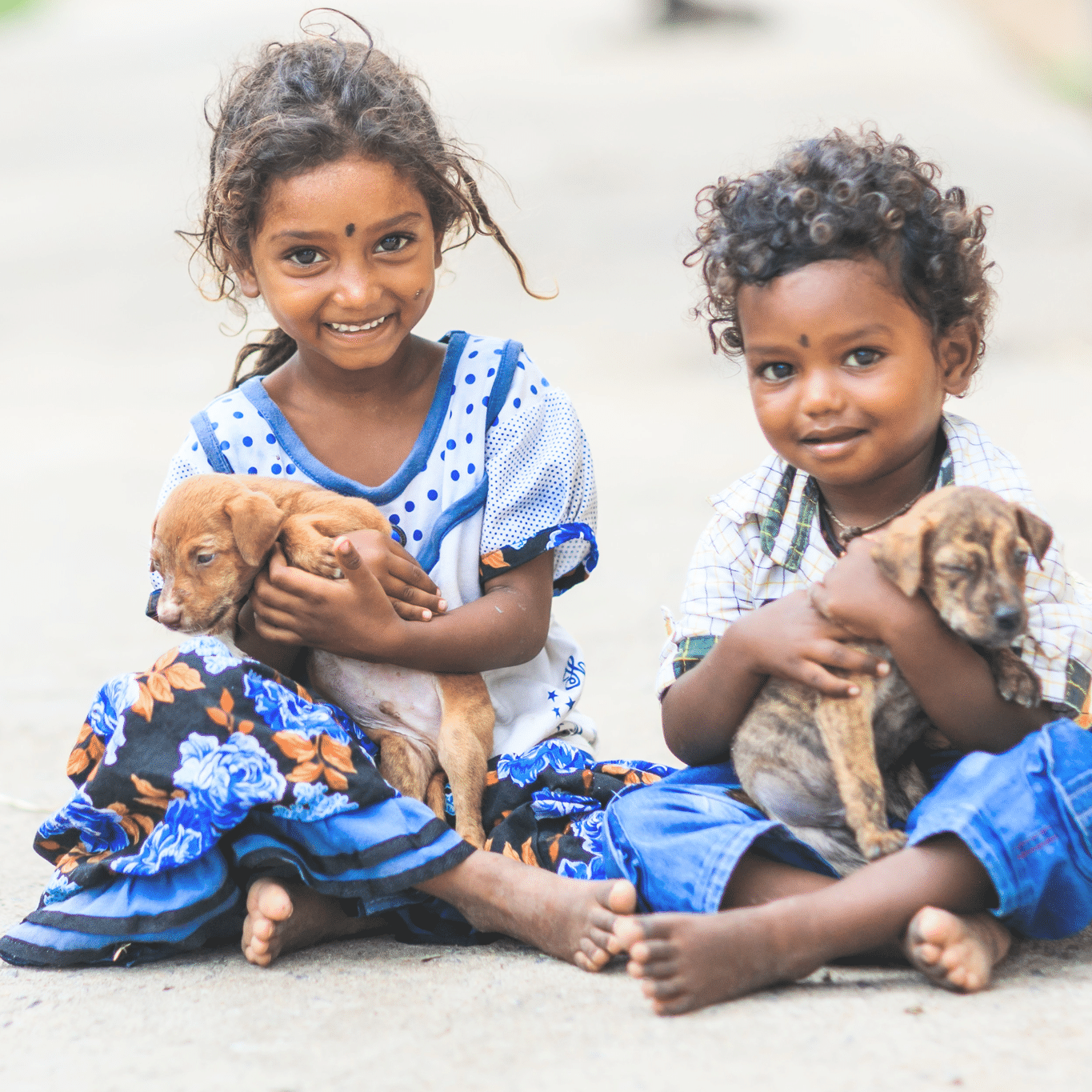 Two children holding puppies with a blurred background