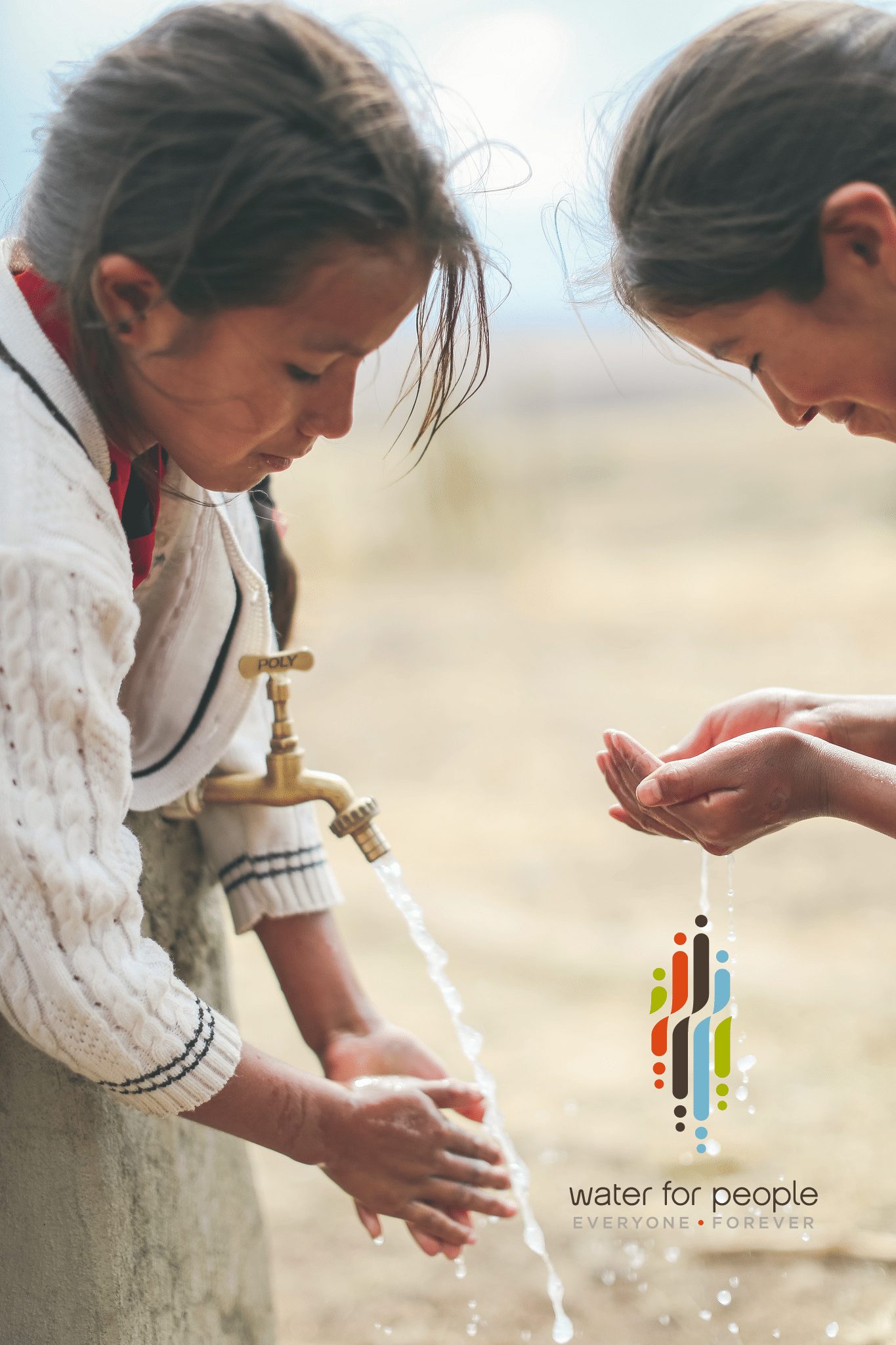 Bolivian girls washing hands in a fresh spring